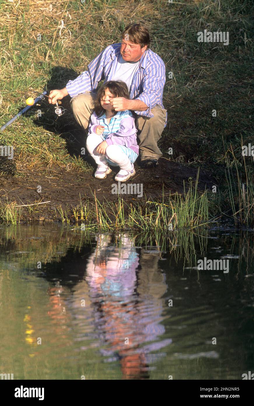 Father and his young daughter fishing in a pond near Kalispell, MT Stock Photo