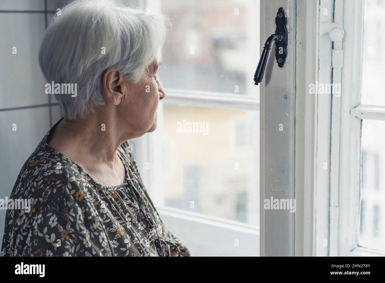 caucasian grandmother sitting next to the window and thinking about her past life. High quality photo Stock Photo