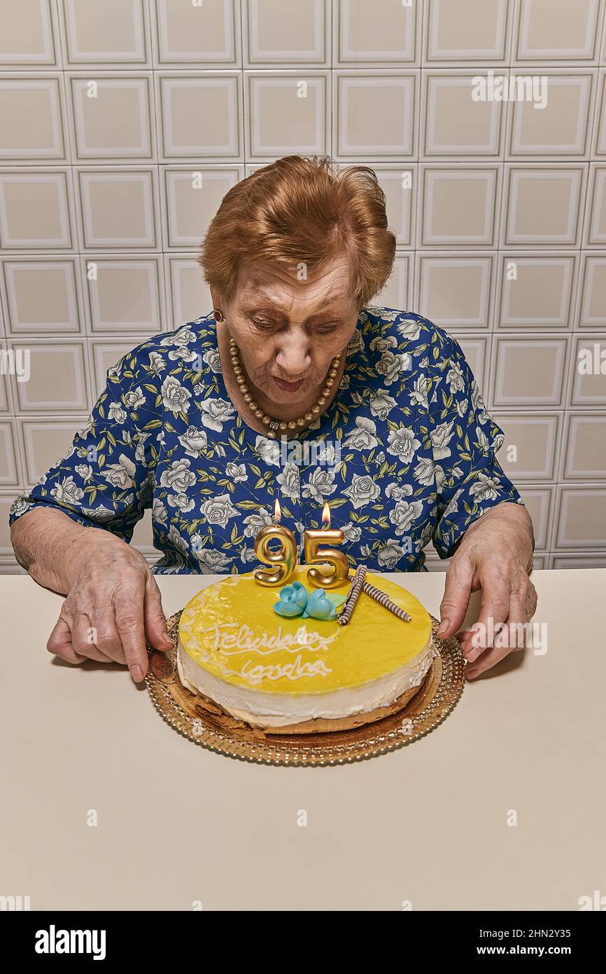 woman in the 90s, blowing candles at her birthday party in an old and