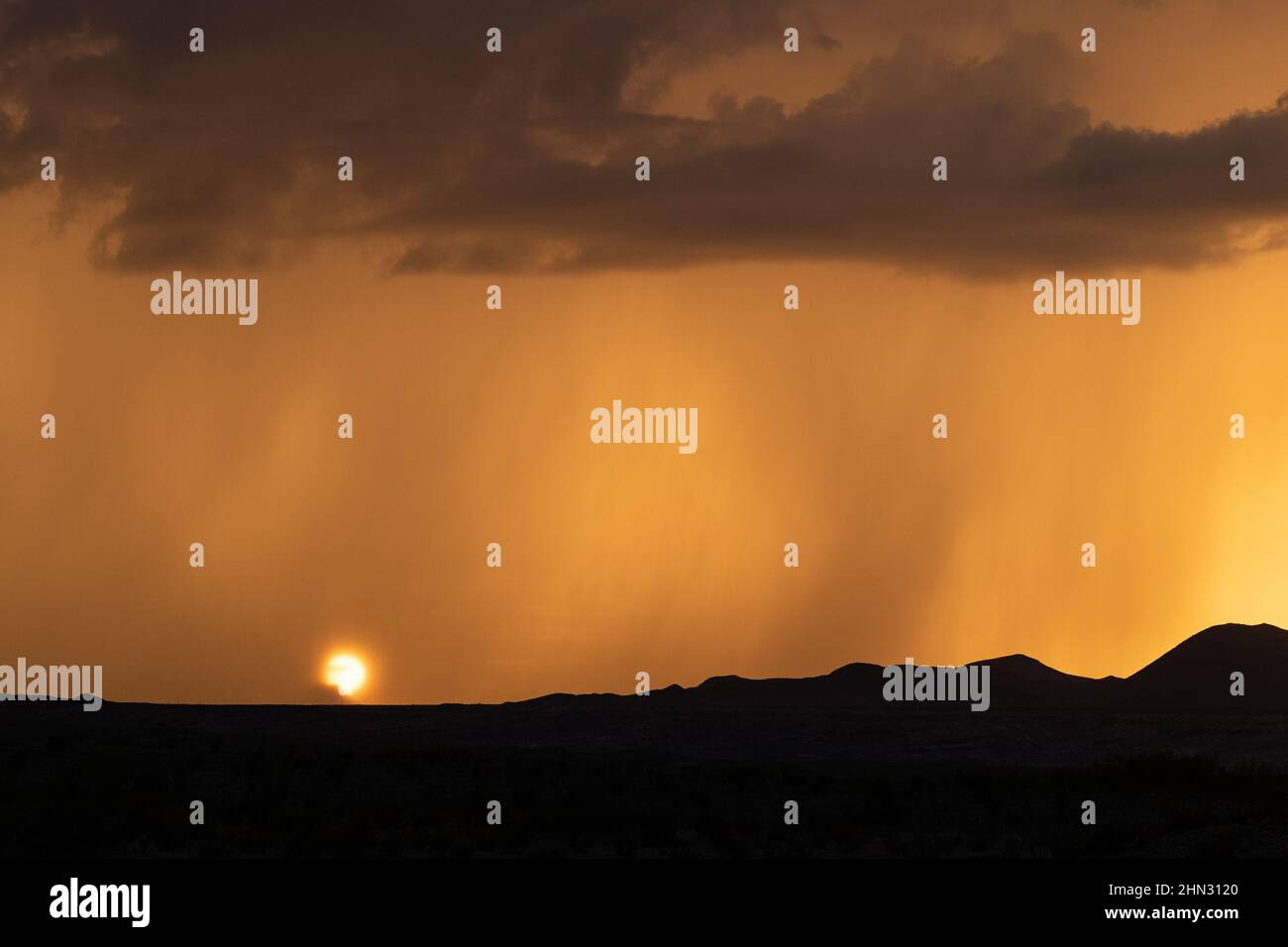 The sun sets behind a veil of rain during the summer monsoon season in the Chihuahuan Desert, Texas. Stock Photo