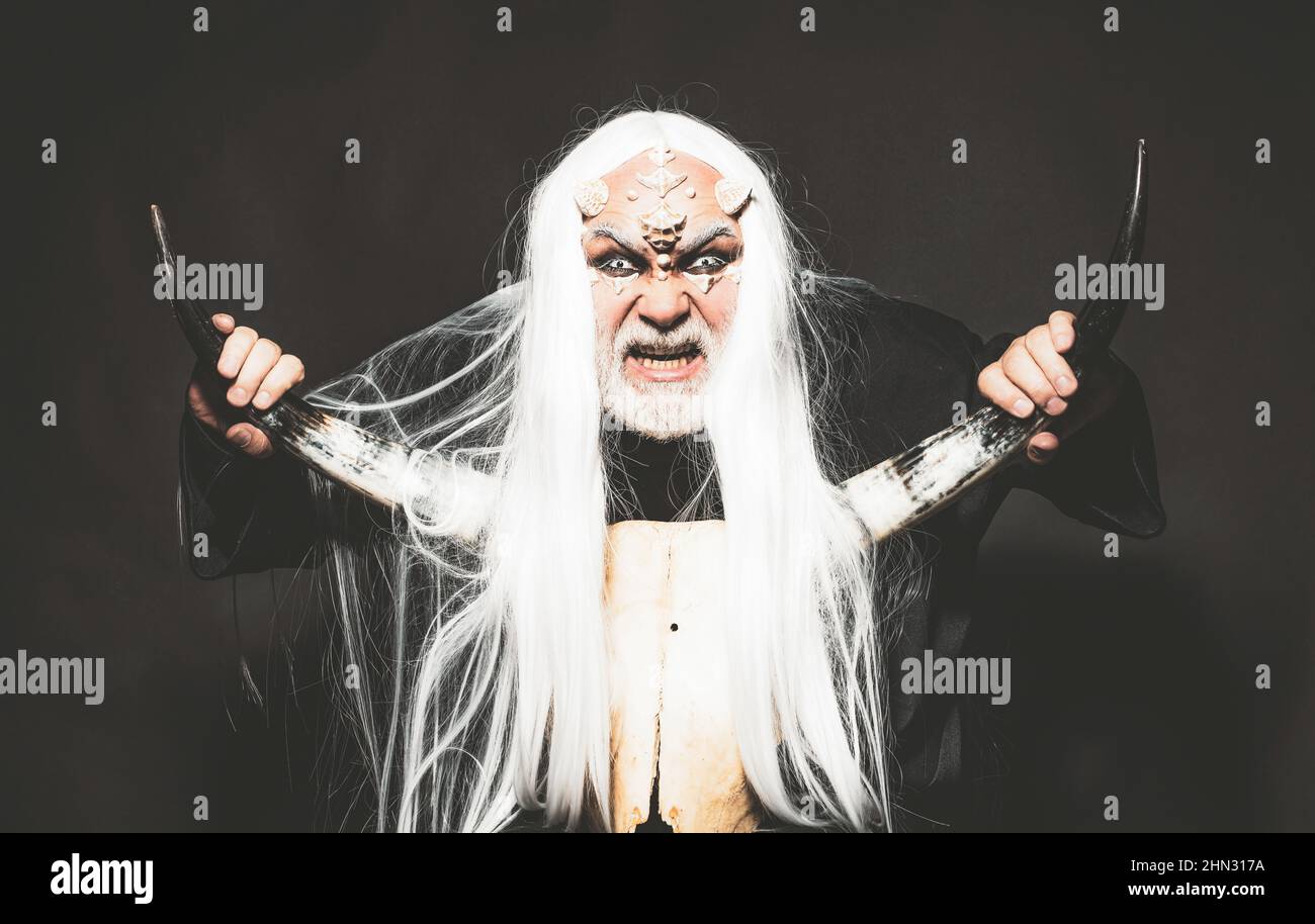 Druid on black background. Alien with dragon skin and grey beard. Ancient alchemy. Monster with white blue eyes. Tree spirit and fantasy concept. Man Stock Photo