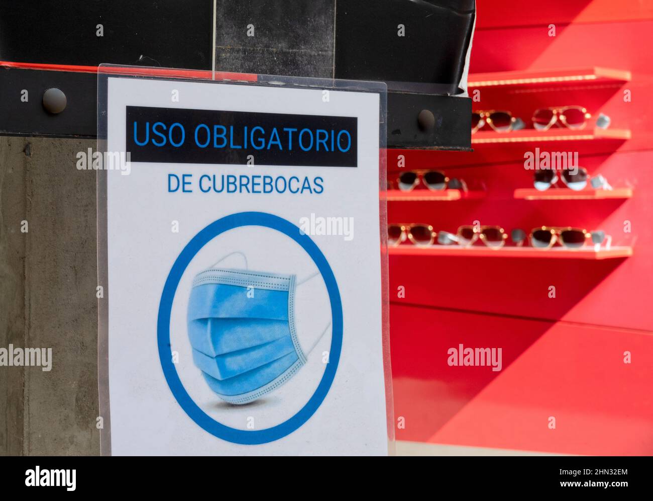 Warning sign at the entrance of an eyeglasses store Symbol shows Wearing a Mask is required in the Spanish language Stock Photo