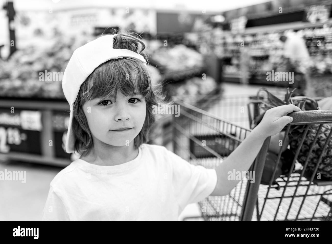 Food store or a supermarket choosing fresh organic carrots. Healthy lifestyle for kids. A boy is shopping in a supermarket. Stock Photo