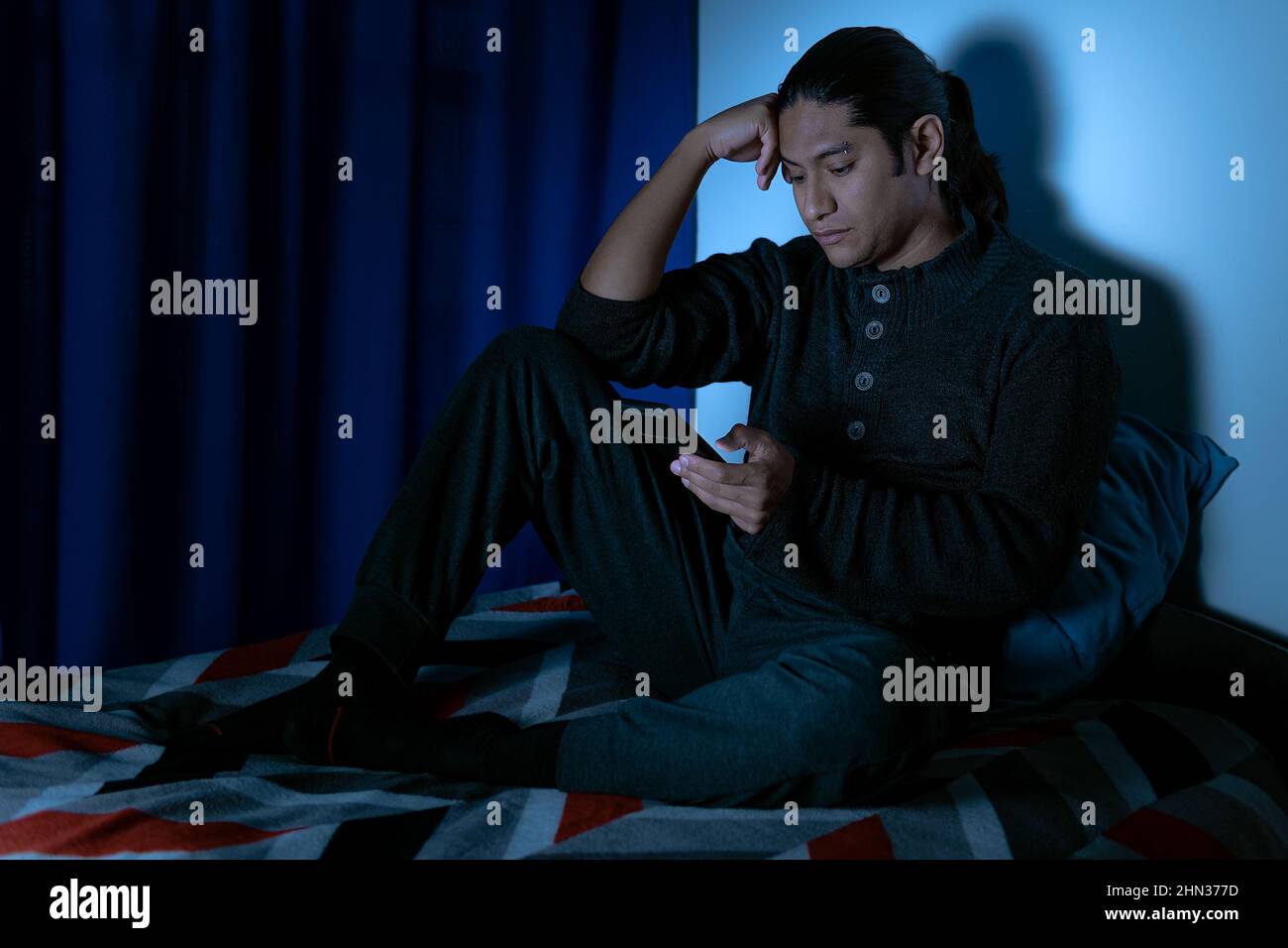 Insomnia, Depressed man sitting up in bed at night, he can't sleep from insomnia Stock Photo