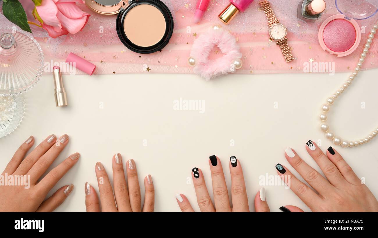 Freelance beauty blogger, nail technician workspace with beauty makeups products, pink accessories, female hands with nails polished on white backgrou Stock Photo