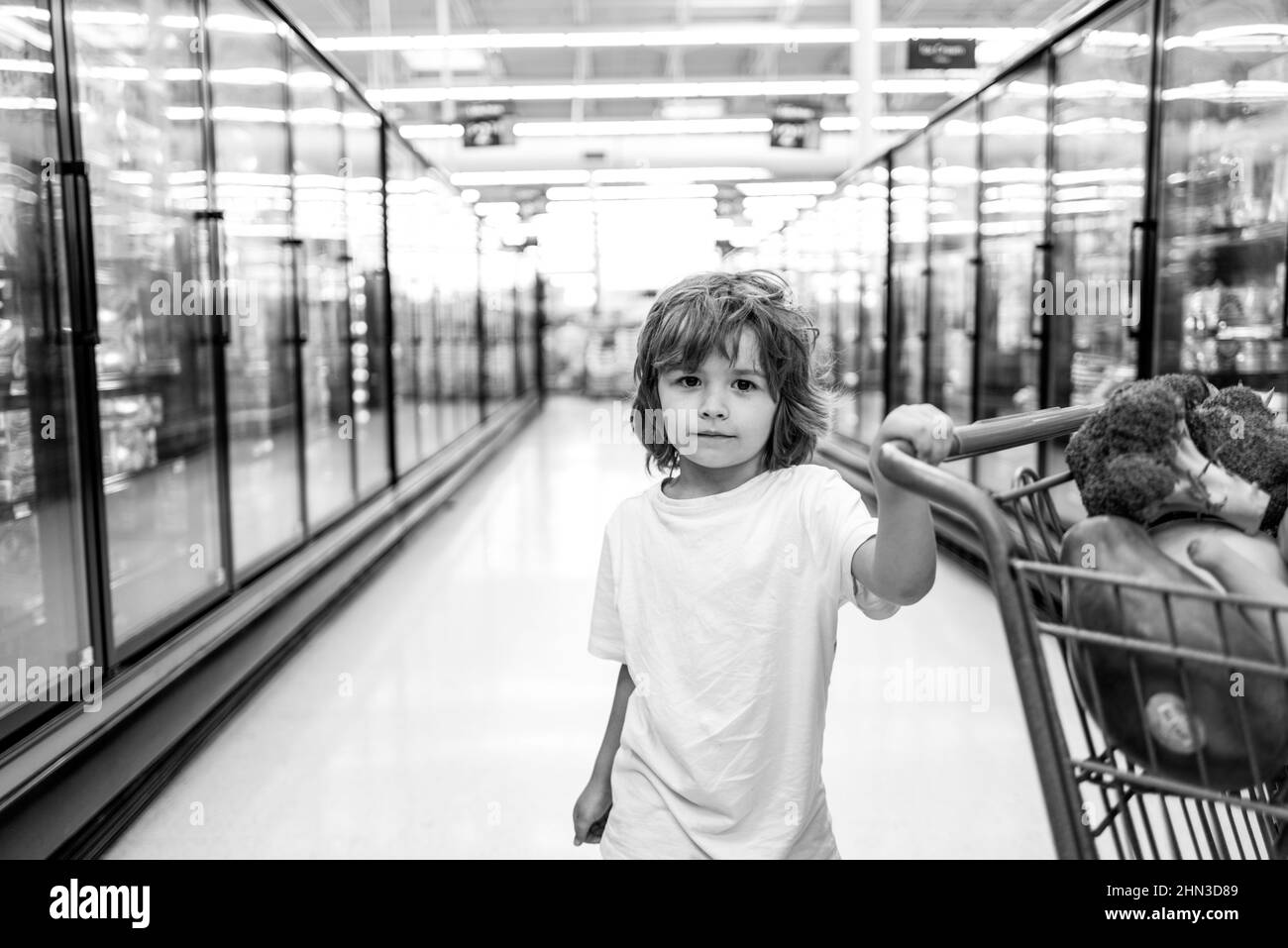 American kid with shopping trolley with in grocery store. A boy is shopping in a supermarket. Stock Photo
