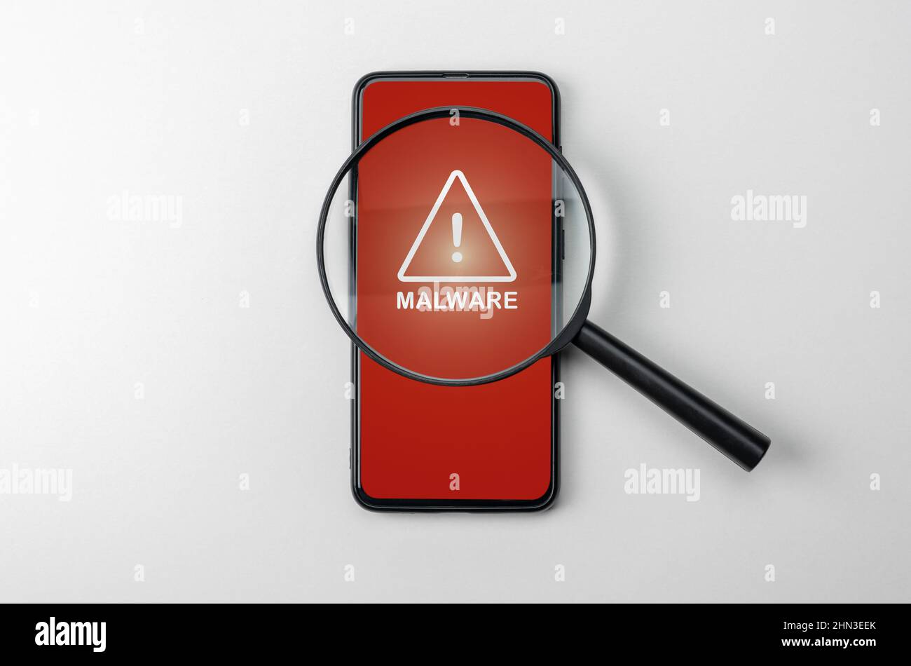 Magnifying glass on cell phone, an alarm sign detecting malware. Virus malware under magnifying glass, anti-virus finds malicious app. Search for malw Stock Photo