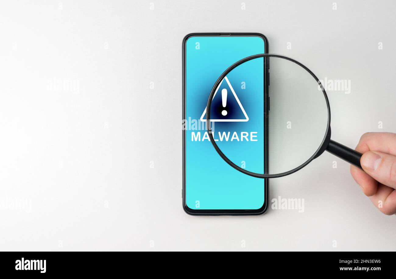 Hand with magnifying glass on cell phone, an alarm sign detecting malware. Virus malware under magnifying glass, anti-virus finds malicious app. Searc Stock Photo