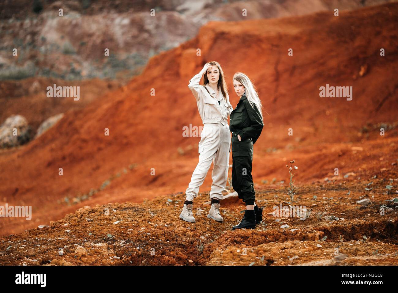 Girls in a post-apocalyptic place, a quarry with red earth and stones in work clothes Stock Photo