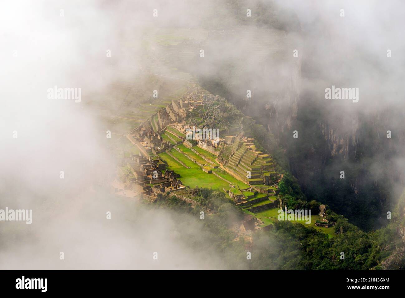 distant view to Machu Picchu ruins through white clouds in Peru Stock ...