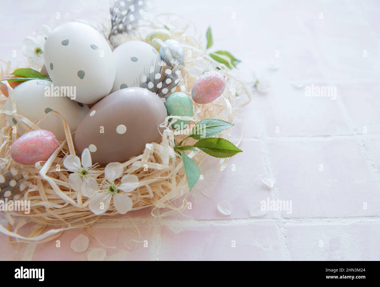 Easter eggs in straw nest on a pink tile background Stock Photo - Alamy