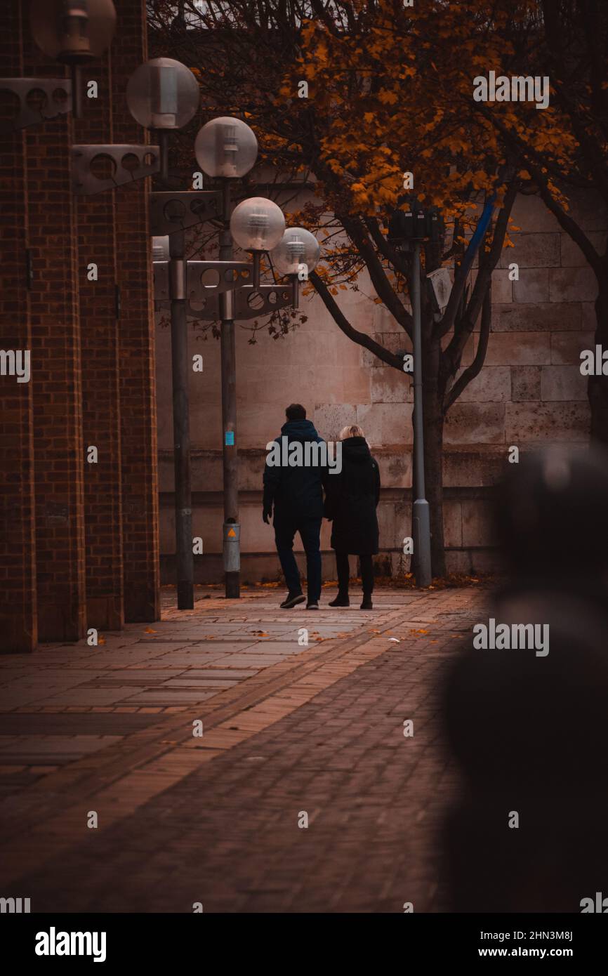 Vertical photo of a couple walking through the park Stock Photo - Alamy