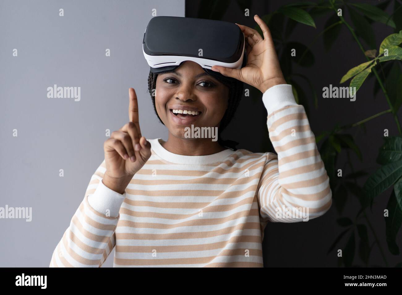 Future of VR. Happy young afro female holding virtual reality headset and looking happily at camera Stock Photo