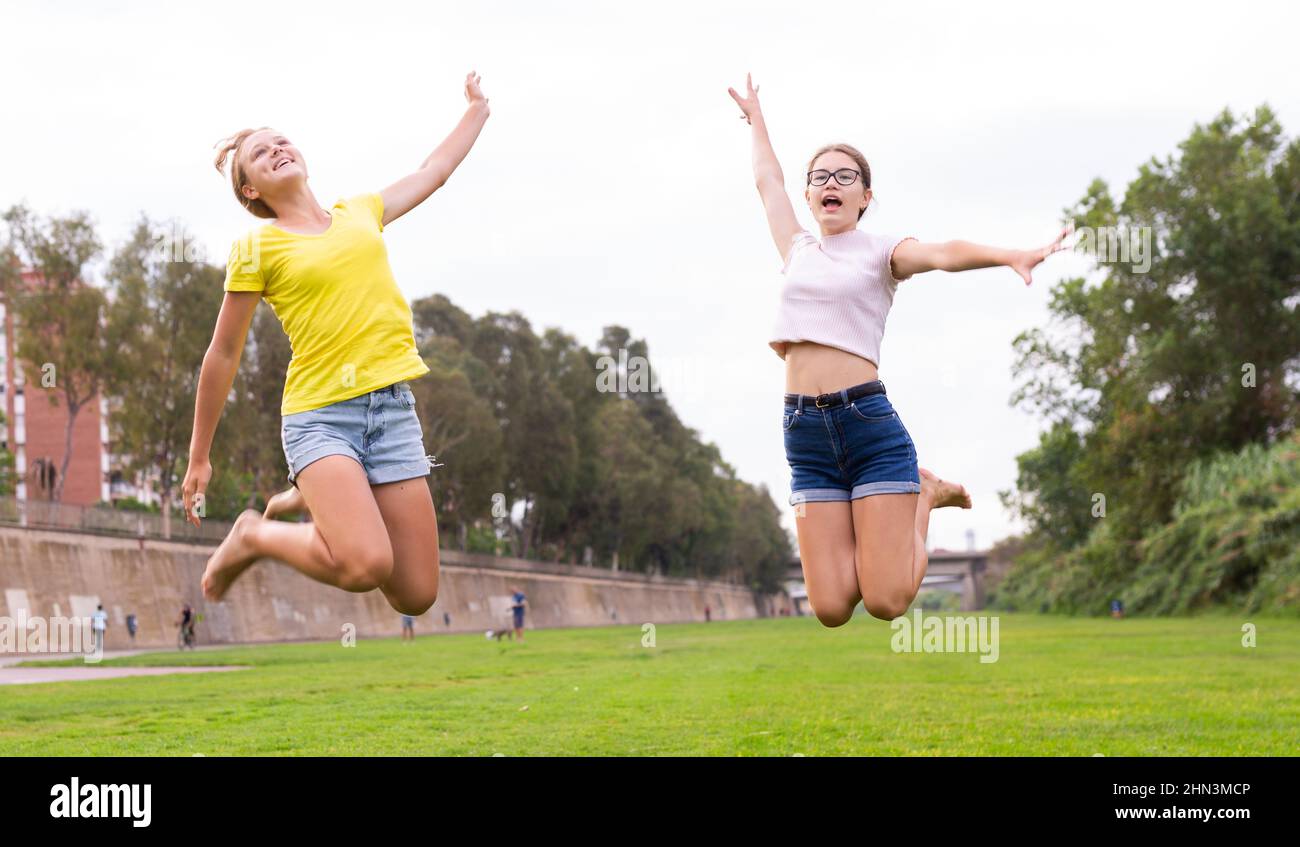 Two young barefoot girls jumping on grass Stock Photo Alamy