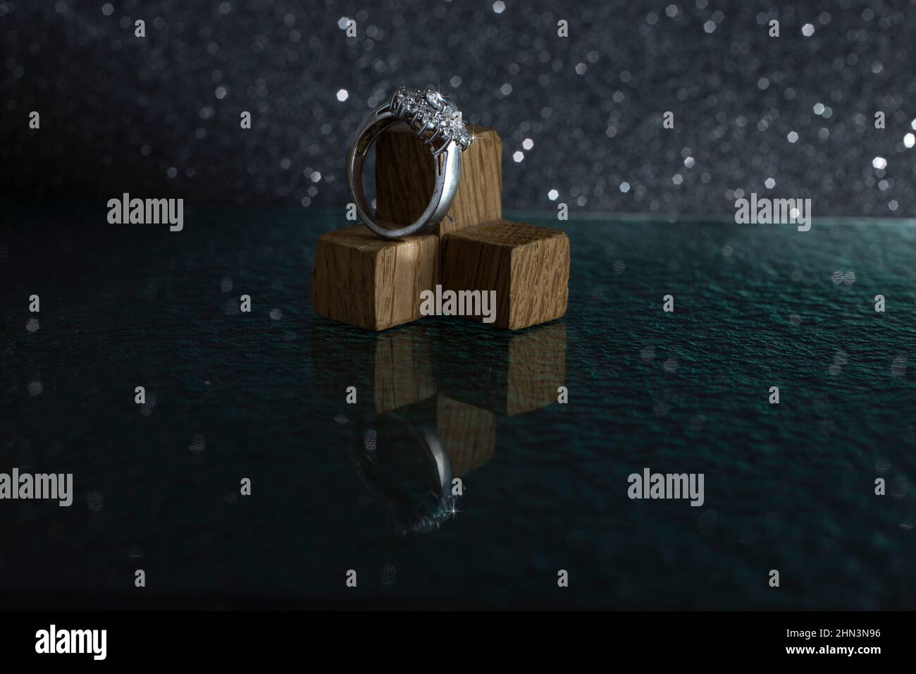 Diamond silver ring on little wood cubes, isolated on black background, with glass reflections Stock Photo