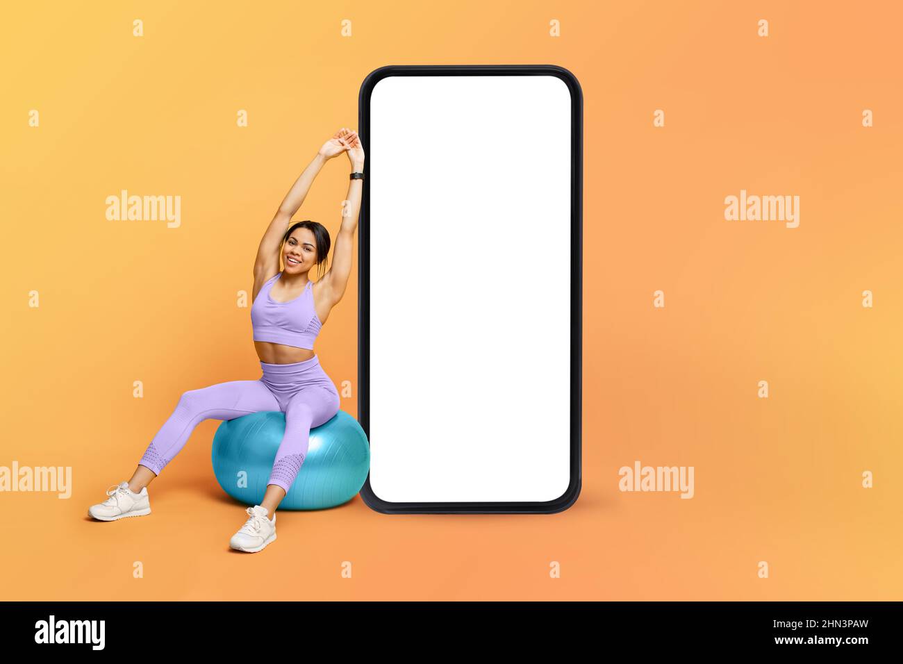 Fitness app. Athletic black lady training on fitness ball near big