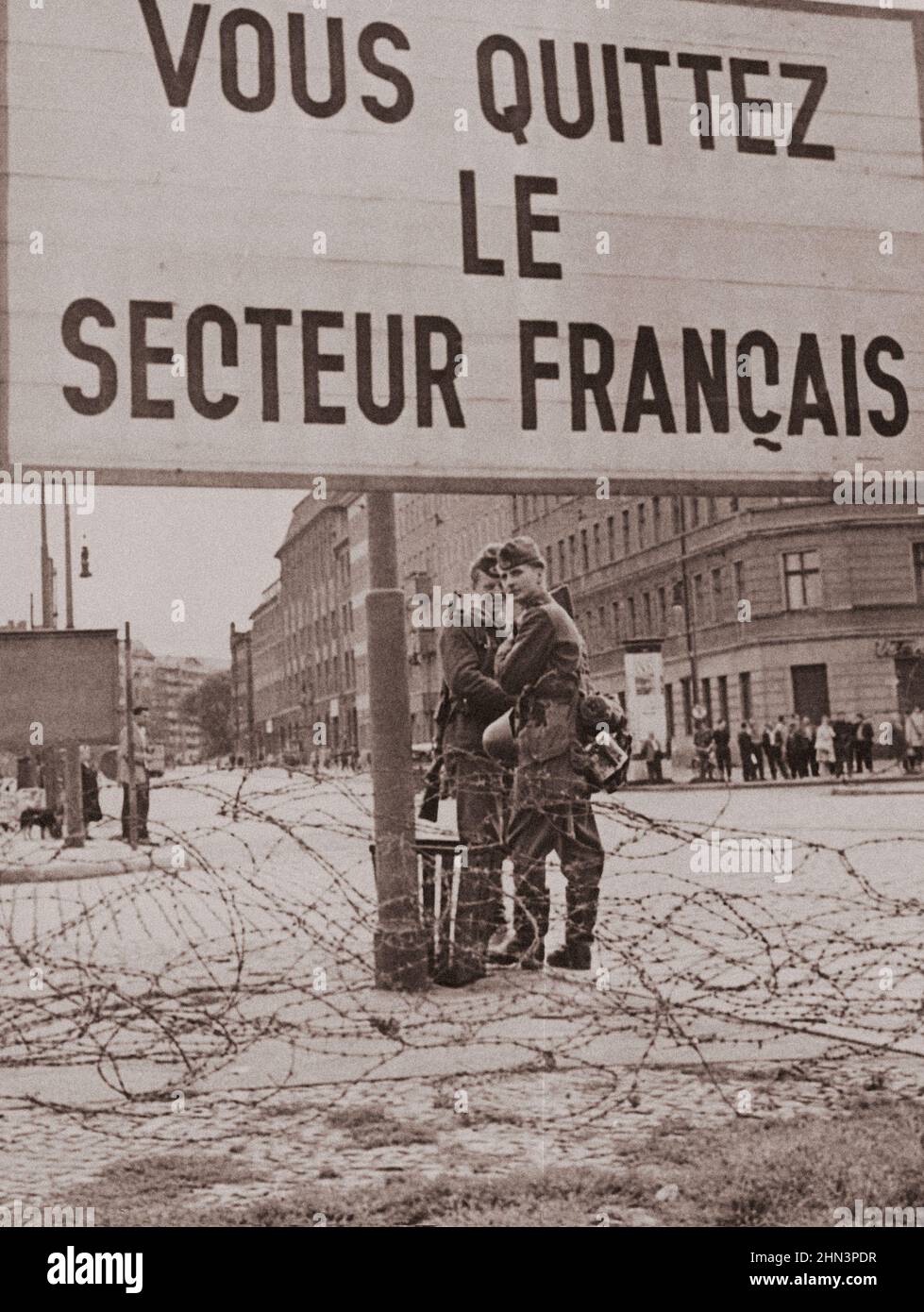 Vintage photo of Berlin Crisis of 1961: Building the Wall. Sign Marking End of the French Sector of West Berlin Is Seen Over the Barbed Wire Fence, Wi Stock Photo