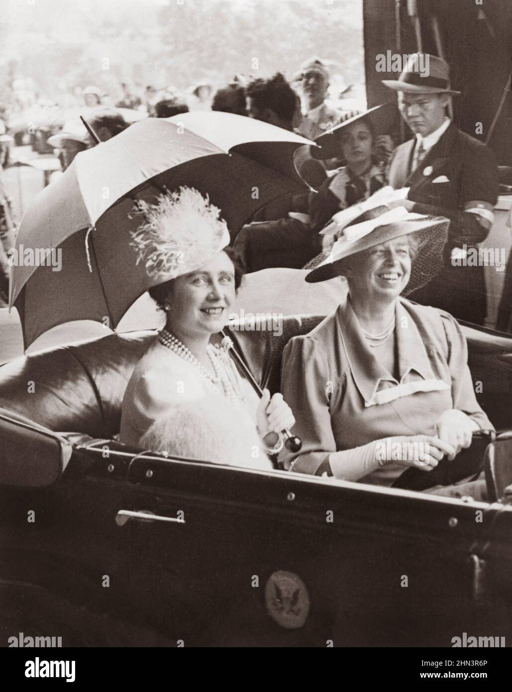 Vintage photo of Mrs. Eleanor Roosevelt and Queen Elizabeth, holding umbrella, in automobile, leaving station for the White House. USA. 1930s Stock Photo