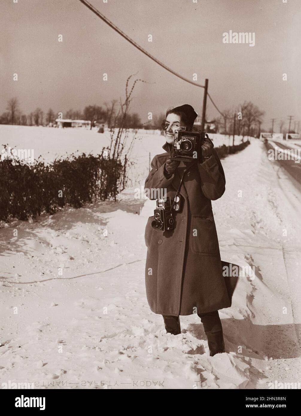 Vintage photo of Marion Post Wolcott standing in snow with cameras. USA, between 1935 and 1942 Stock Photo