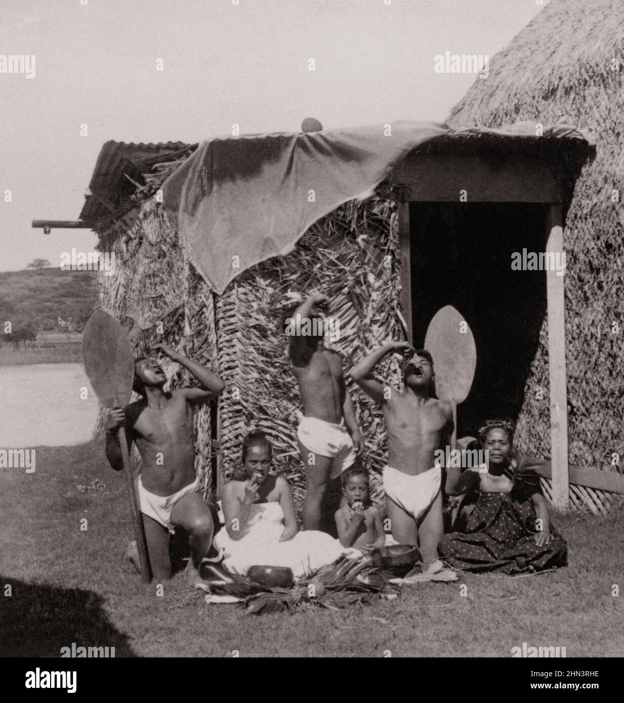 Vintage photo of group of Native Kanaka Maoli eating poi, Hawaiian Islands (in front of grass hut). 1896 Native Hawaiians are the Indigenous Polynesia Stock Photo