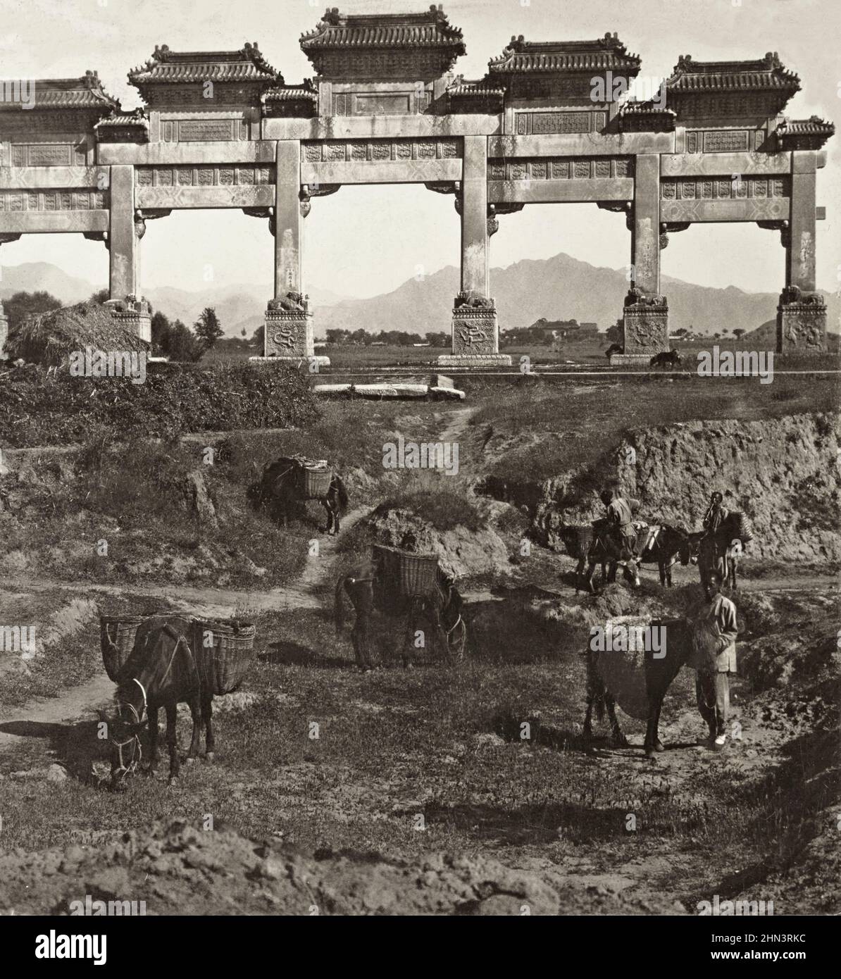 Vintage photo of Chinese men in traditional dress and queue with loaded donkeys in the foreground of beautiful marble pailow, entrance to avenue of st Stock Photo