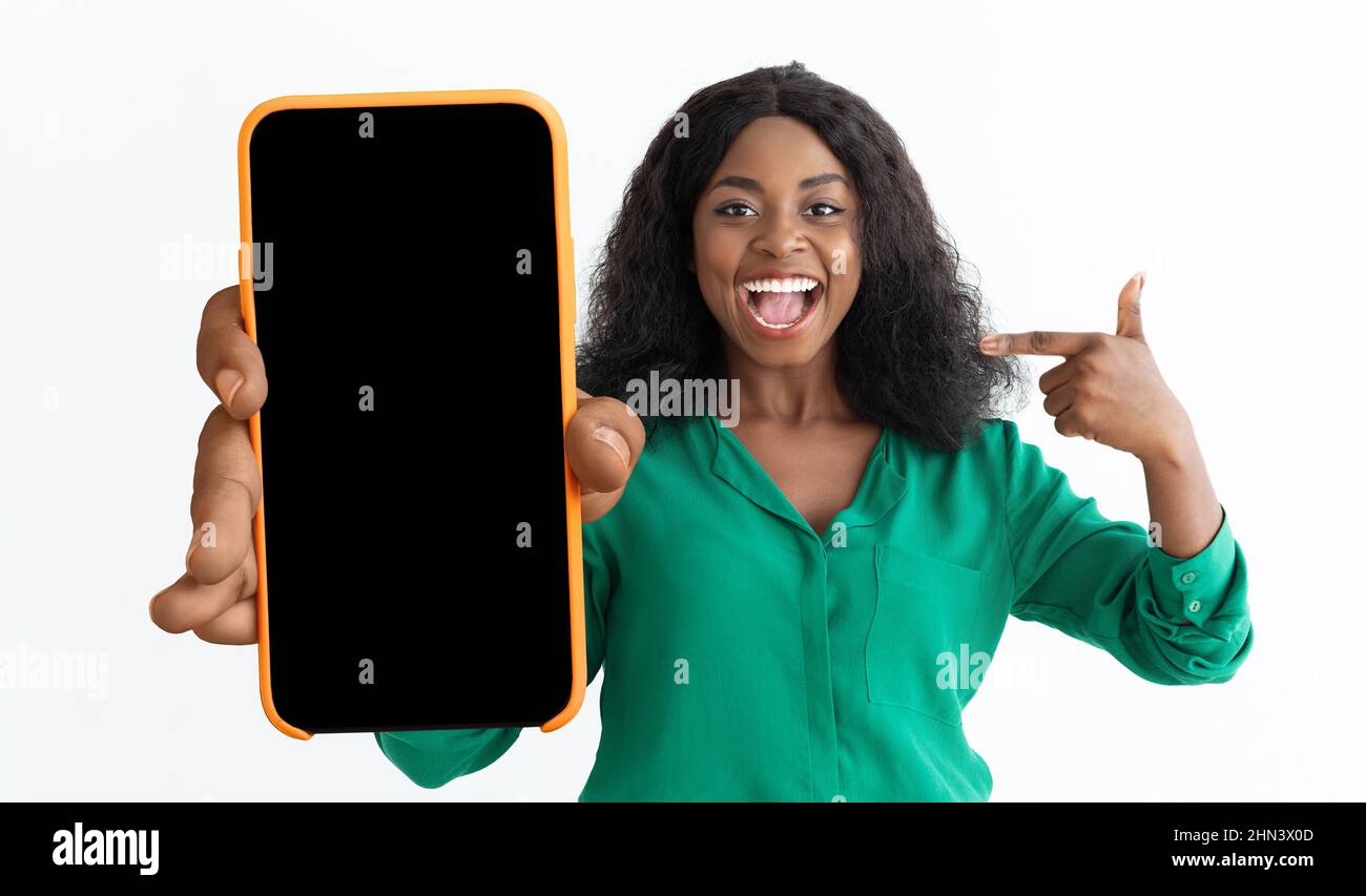 Excited black woman pointing at cellphone with black empty screen Stock ...