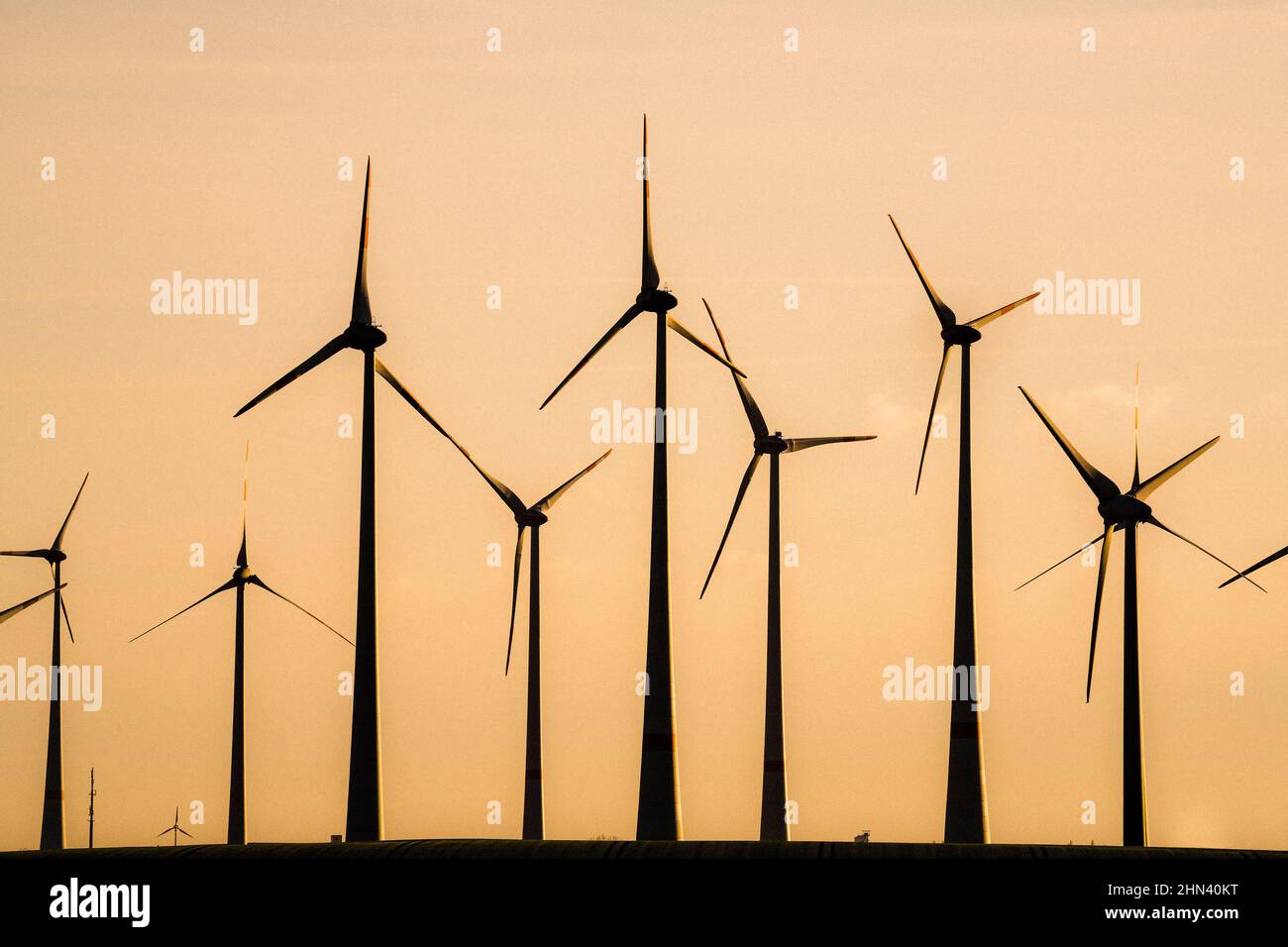 Silhouetted wind turbines against golden sunset sky, Germany Stock ...