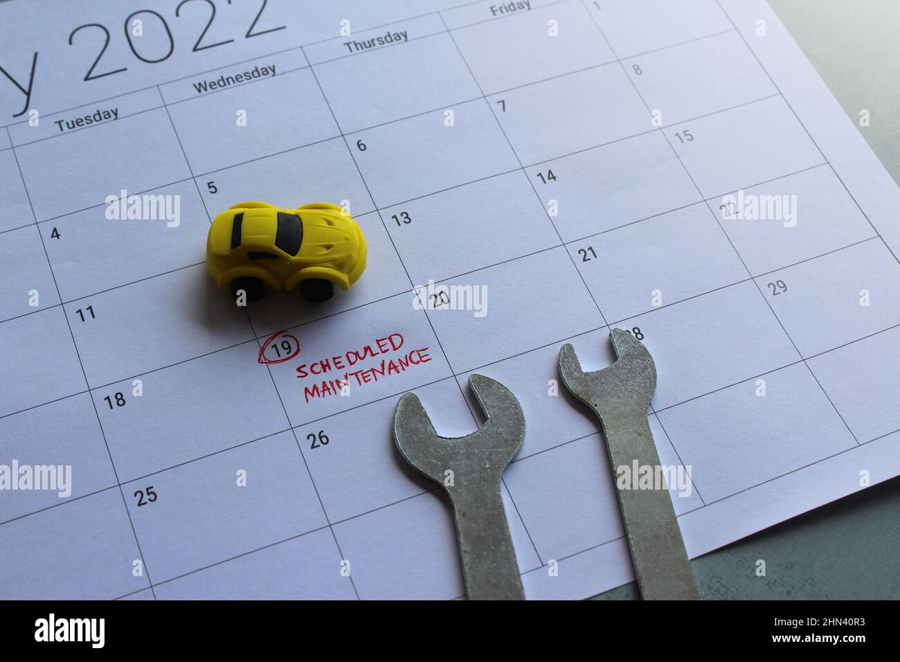 Car scheduled maintenance concept. Toy car, spanner and calendar with text SCHEDULED MAINTENANCE Stock Photo