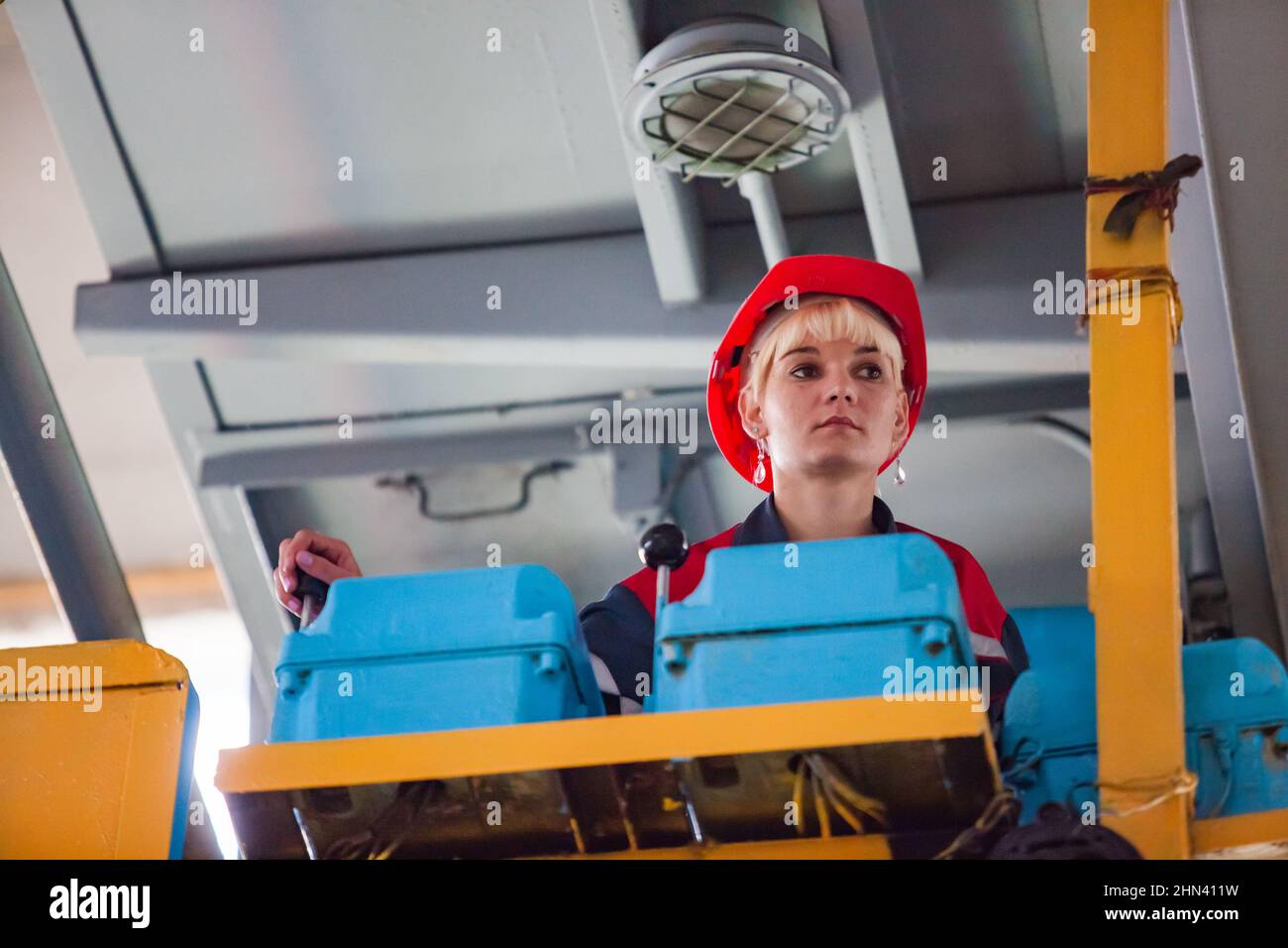 Karagandy,Kazakhstan-June 08,2012: KazBELAZ quarry trucks BELAZ service and repairing plant. Young woman crane operator in cabin. Blue switchers with Stock Photo