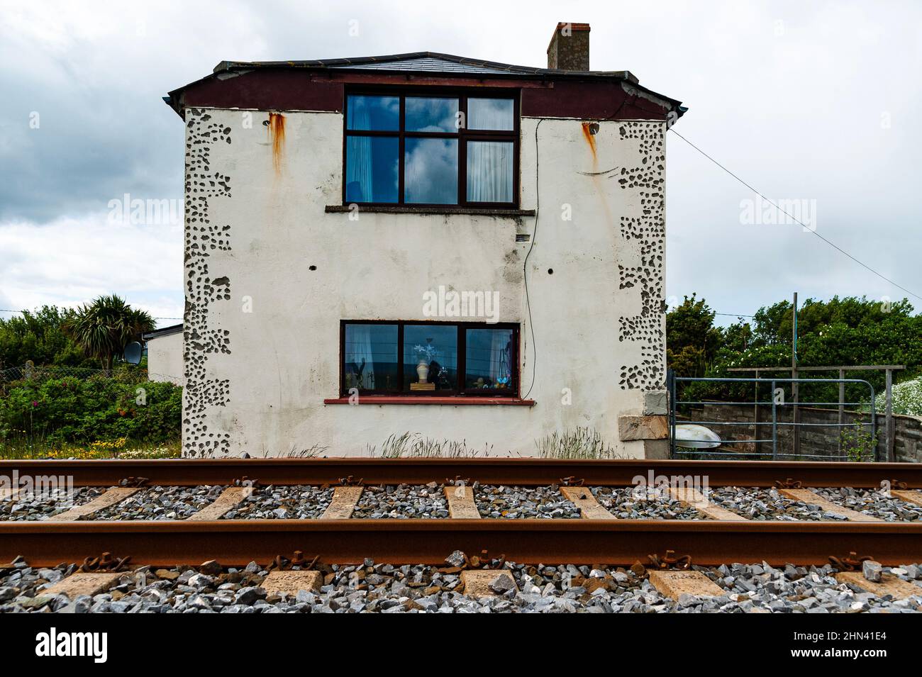 Derelict building close to railroad means sleepless nights. Dilapidated house by a railway or train tracks. Forsaken home conveys solitude concept Stock Photo