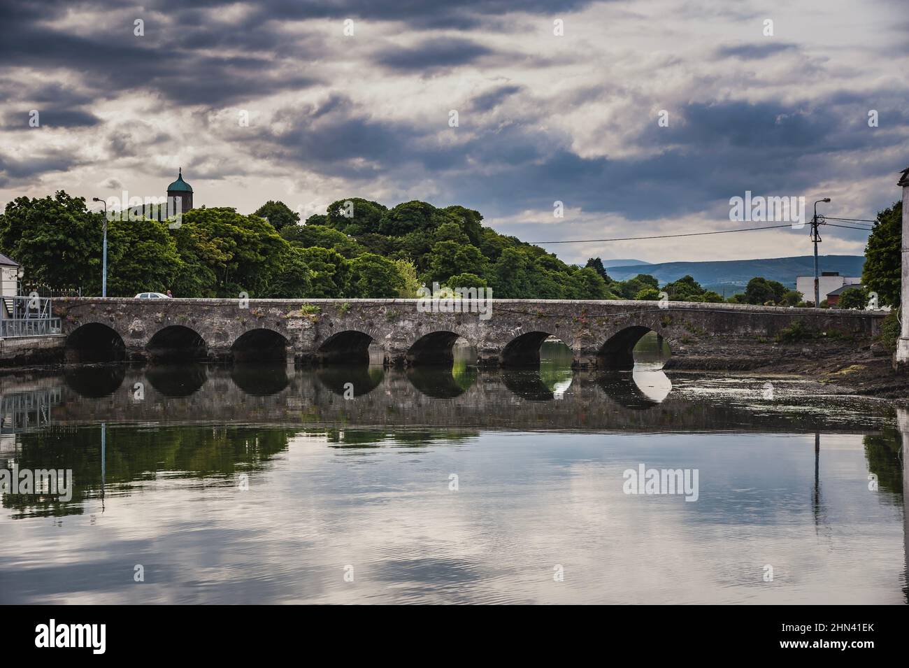 Old arched bridge crossing the Vartry River, Wicklow town. Typical Irish road on a historical stone bridge across calm water in a countryside village Stock Photo