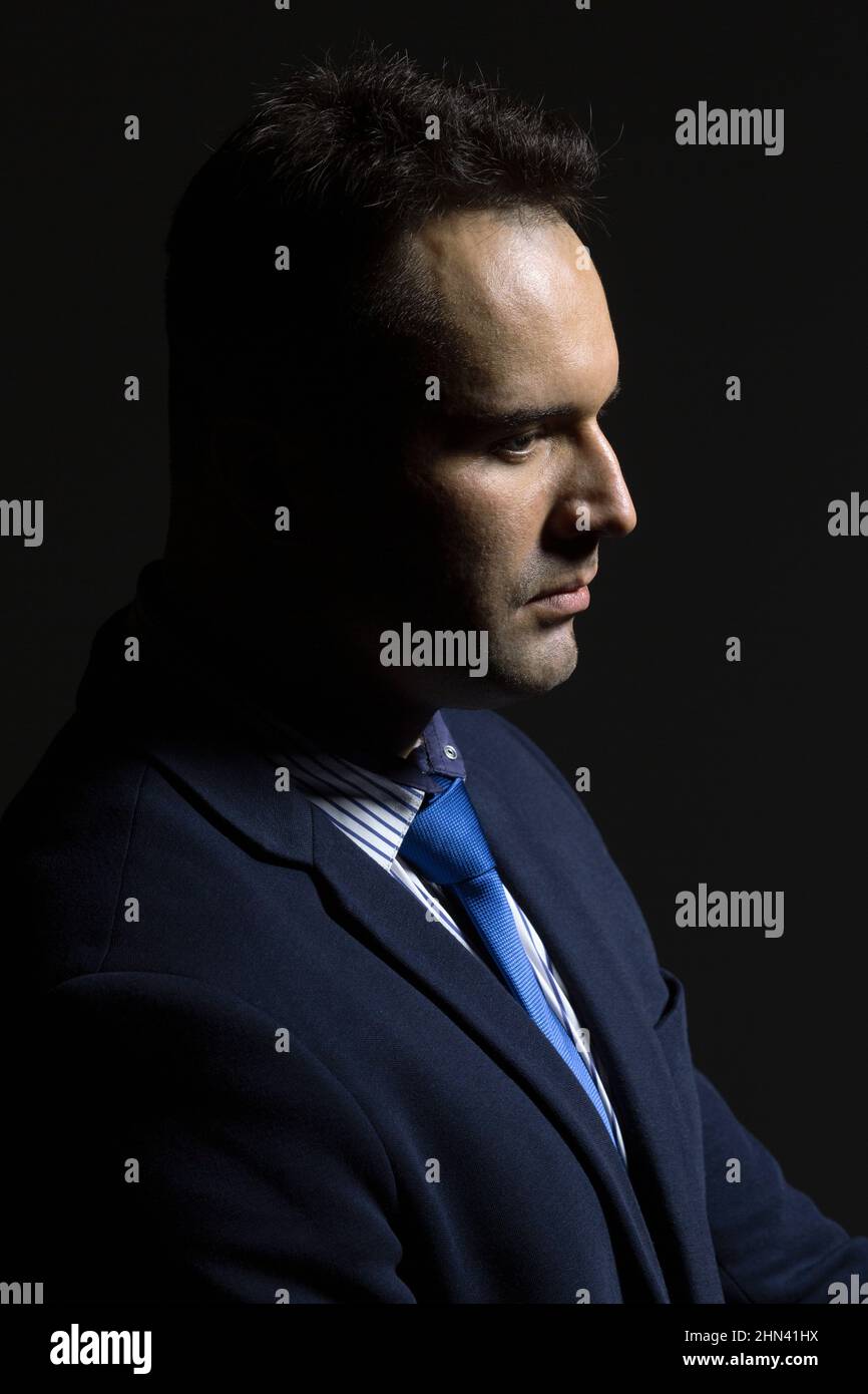 Profile portrait serious, handsome businessman on black background Stock Photo