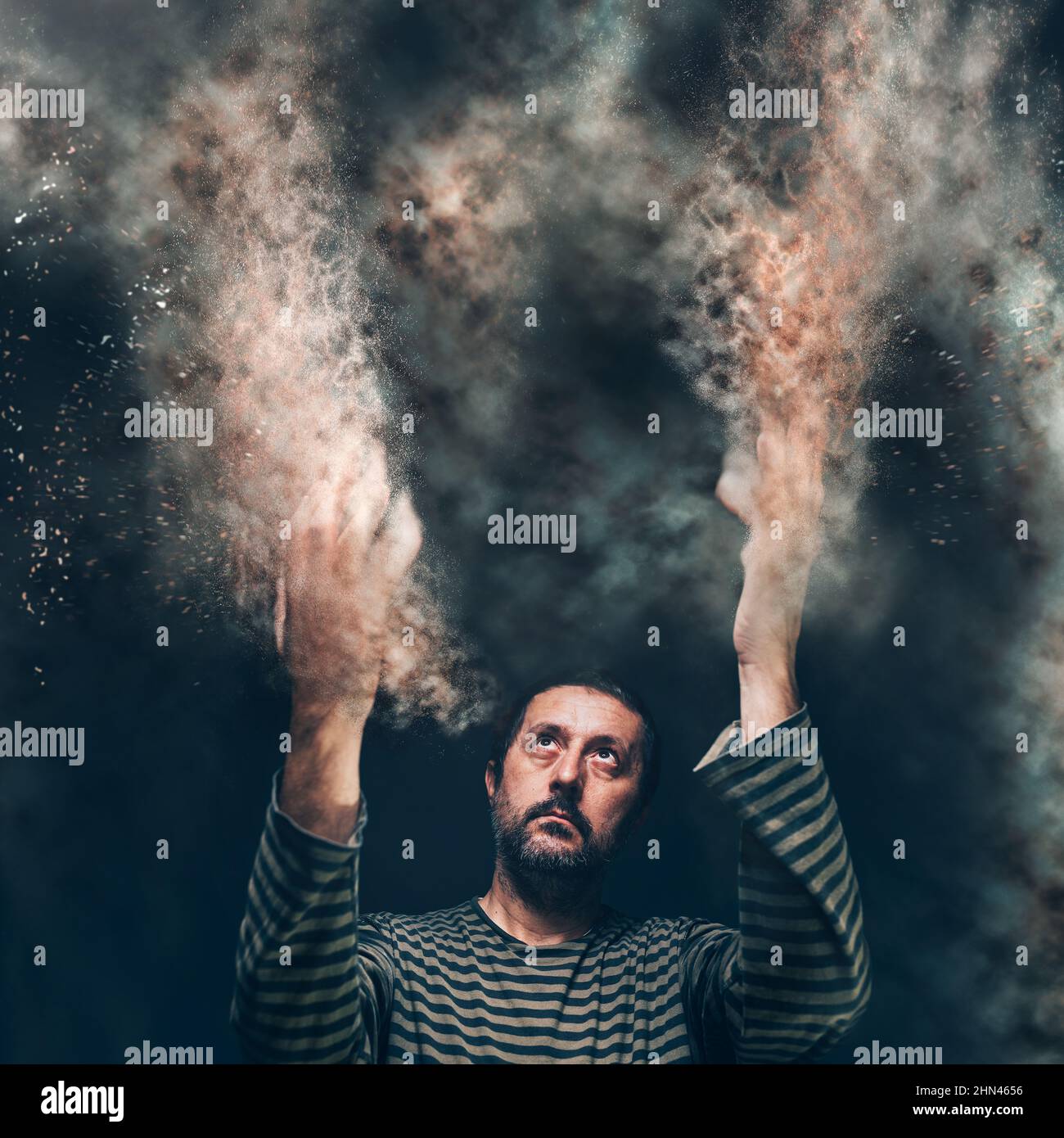 Dissolving in sand and disappearing, religious concept for dying and leaving this world, man with hands raised looking up, selective focus Stock Photo