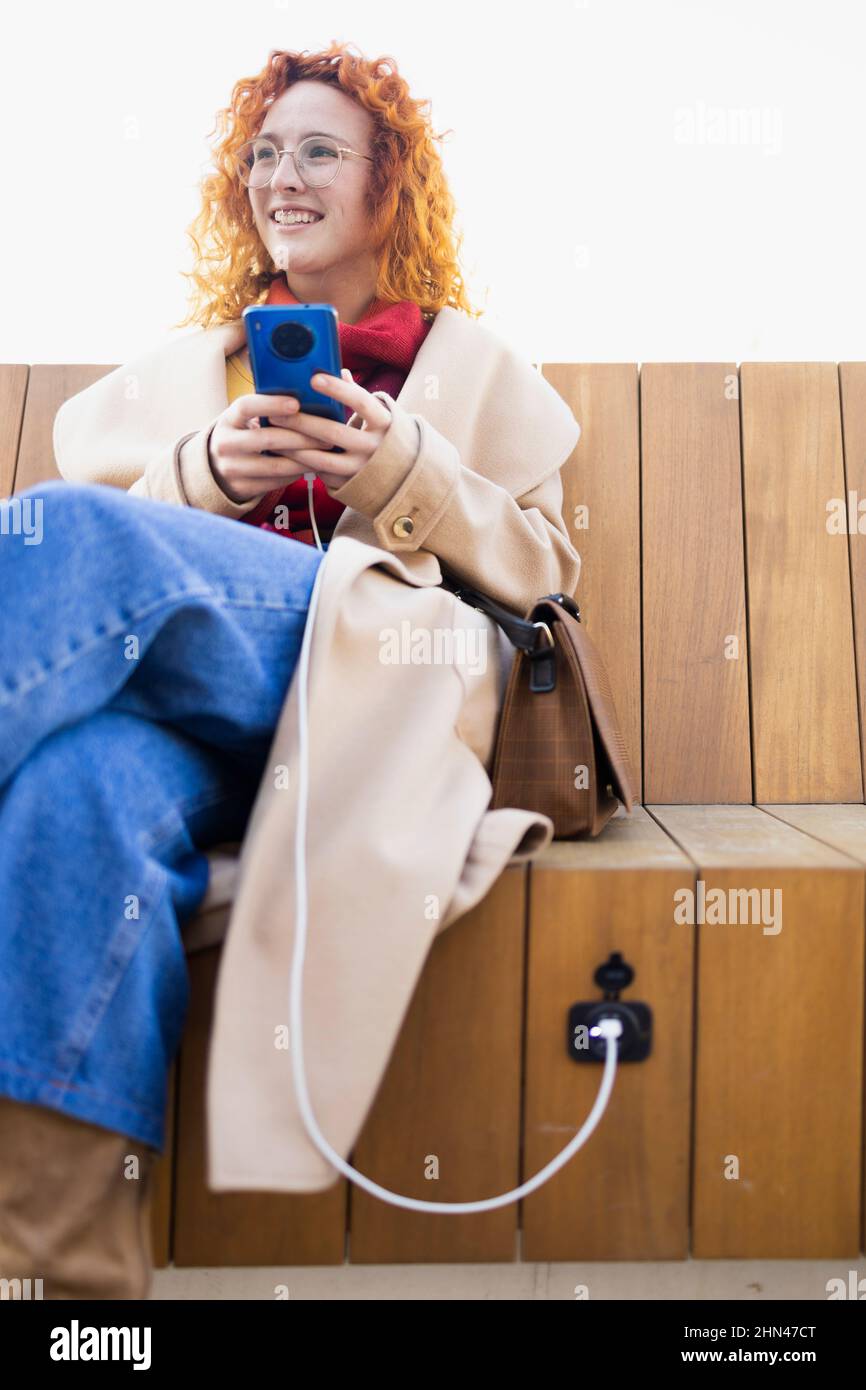 Charging a smartphone on a new smart bench Stock Photo