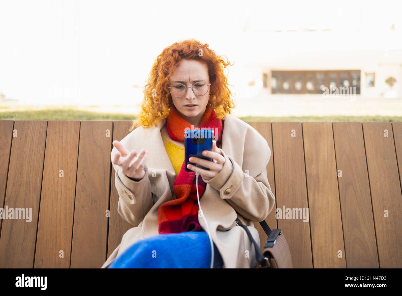 Concerned young woman reading some disturbing news on her smartphone Stock Photo