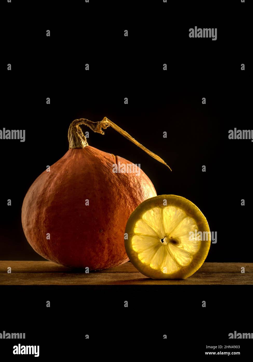 still life showing a pumpkin and a slice of lemon on a black background Stock Photo