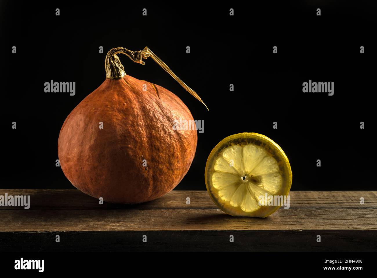 still life showing a pumpkin and a slice of lemon on a black background Stock Photo