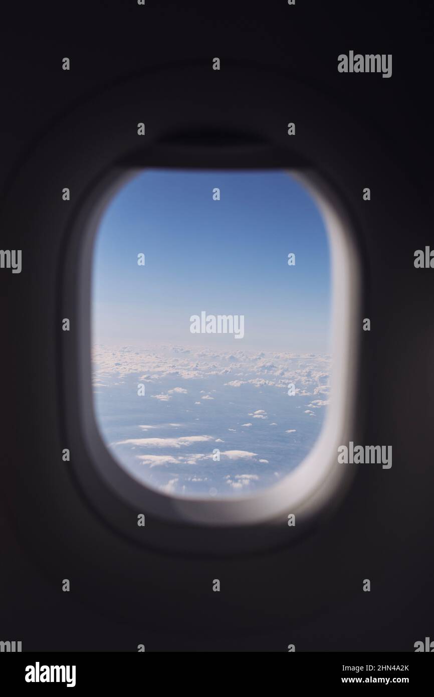 Window of airplane during flight above clouds on beautiful sunny day. Stock Photo