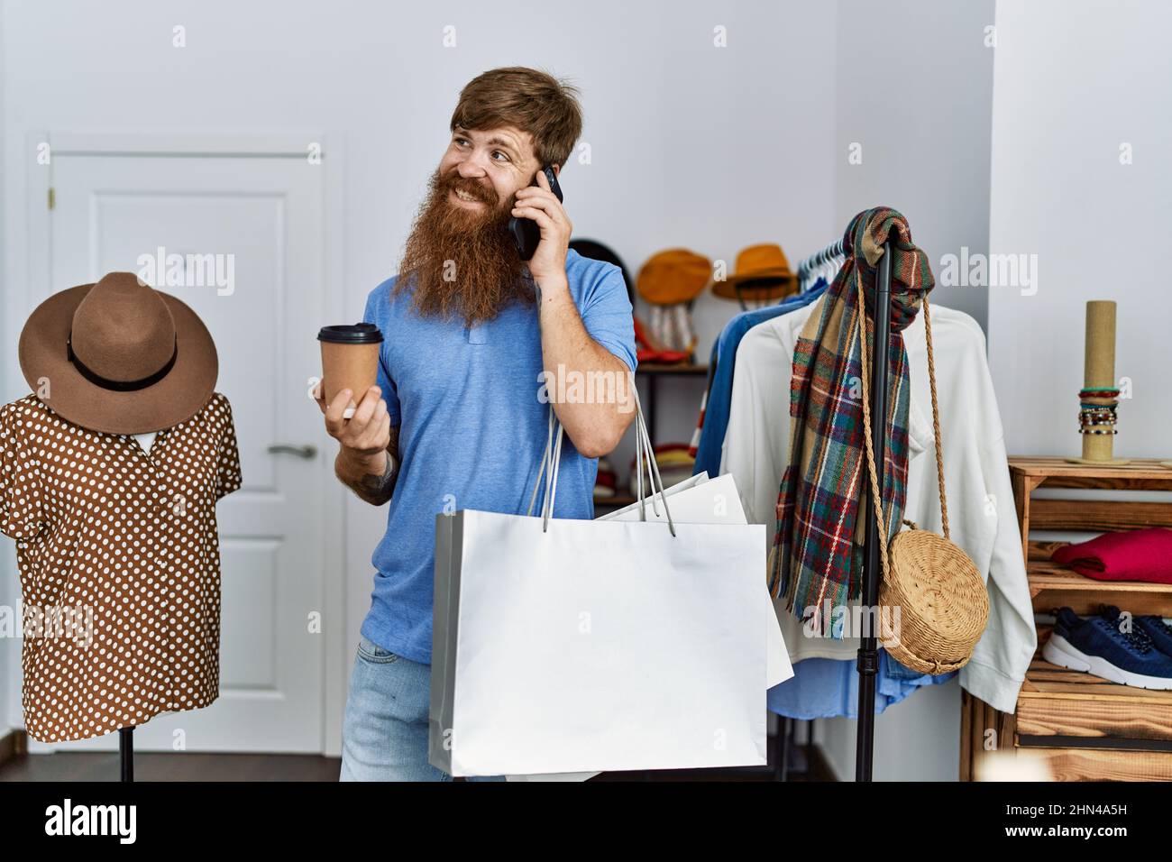 Young redhead customer man talking on the smartphone and drinking