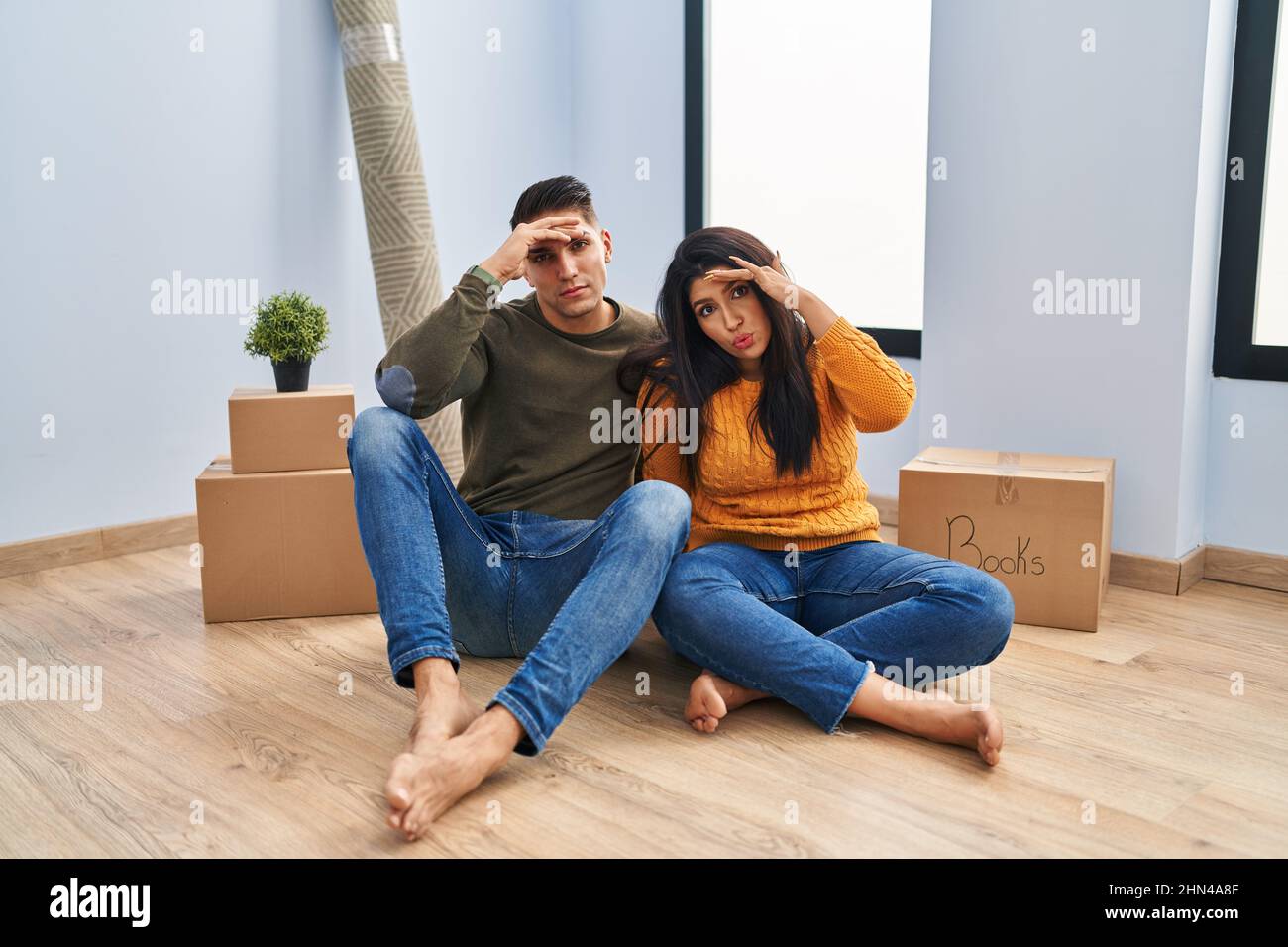 Young couple sitting on the floor at new home worried and stressed