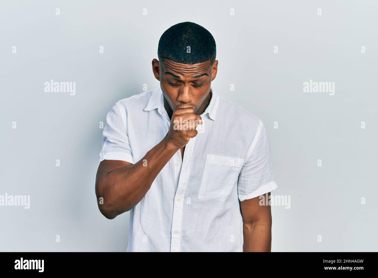 Young black man wearing casual white shirt feeling unwell and coughing ...