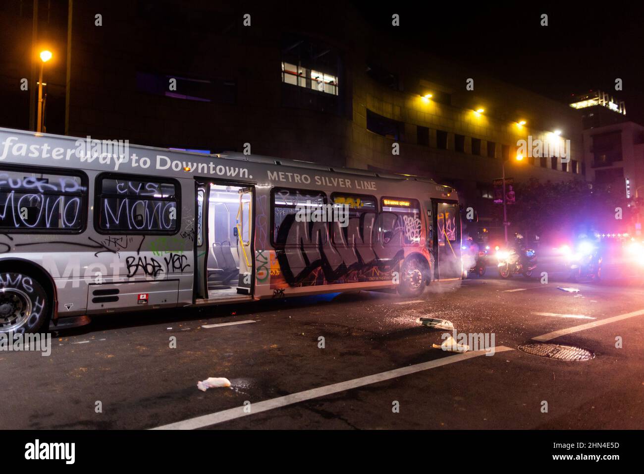 Crowds are cleared from a vandalized Metro bus by Los Angeles Police  officers in riot gear as football fans celebrate after the Los Angels Rams  defeated the Cincinnati Bengals during the NFL