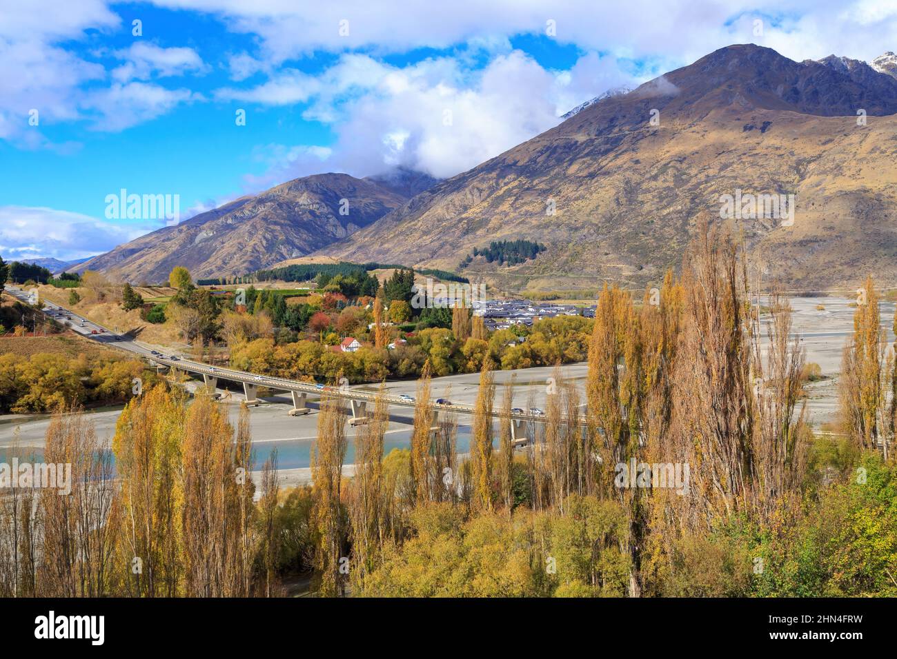 Autumn landscape near Queenstown, New Zealand. A road bridge crosses the Shotover River. At right is the Remarkables mountain range Stock Photo