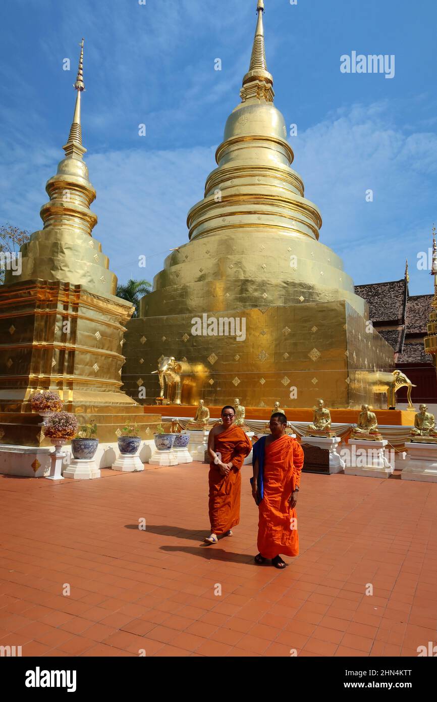 Two Buddhist Monks walking in front of the golden stupa of Wat Phra Singh temple, Chiang Mai, Thailand. Stock Photo