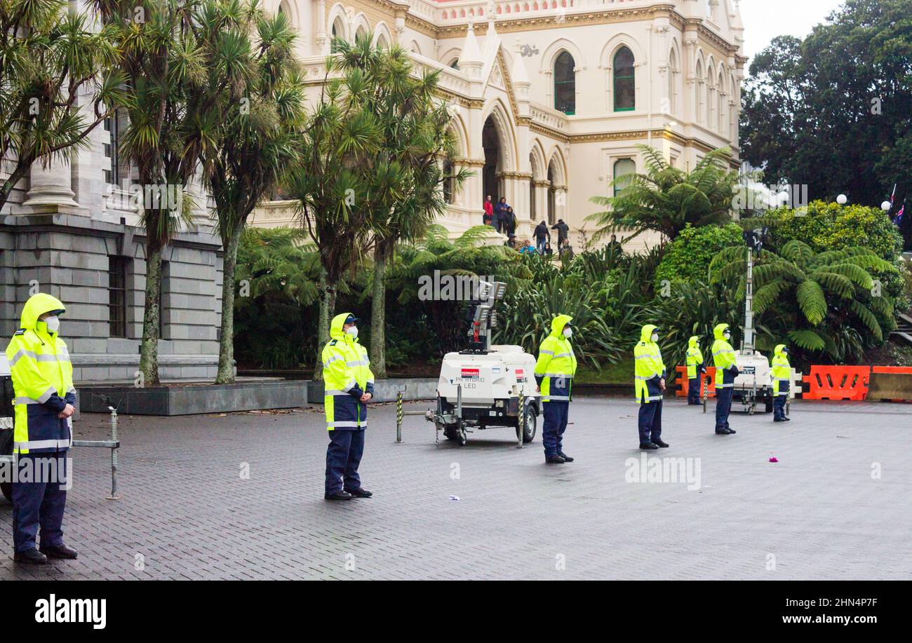 Wellington, New Zealand. February 13, 2022:Police stand guard at Parliament facing the large crowd of protestors behind a barricade. Stock Photo