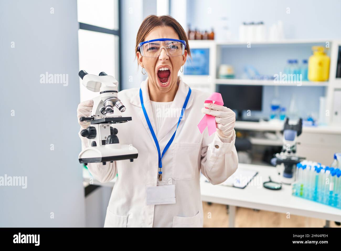 Young brunette woman working at scientist laboratory holding pink ...