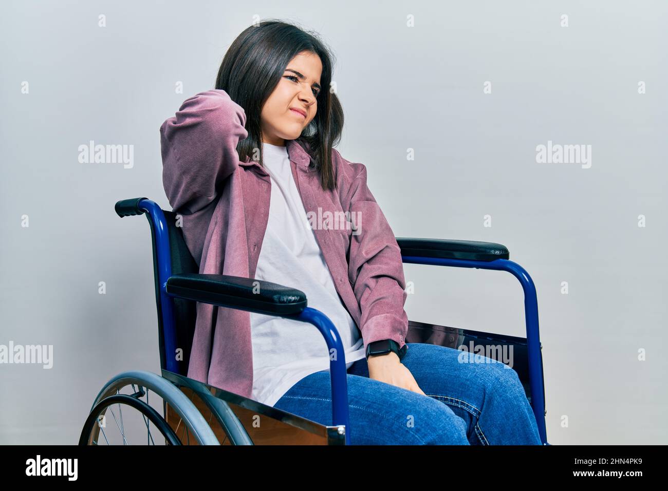 Young woman sitting on wheelchair suffering of neck ache