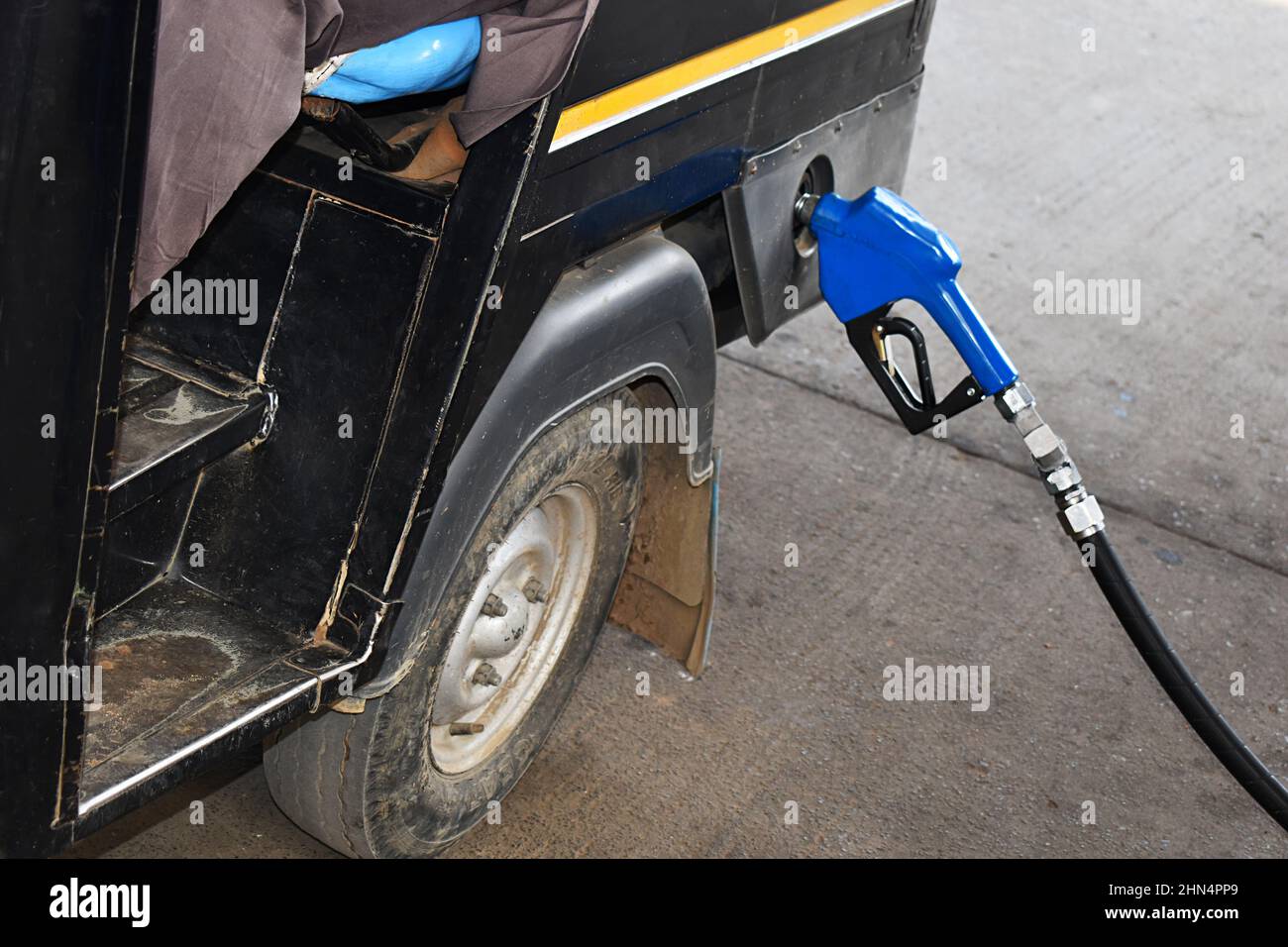Close-up nozzle - Fuel Pump filling a Auto rickshaw at a Petrol Station. Bhopal city, Madhya Pradesh, India. Stock Photo
