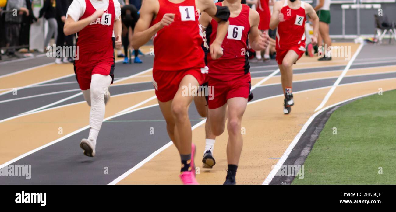 High school boys running in a track and field race on an indoor track