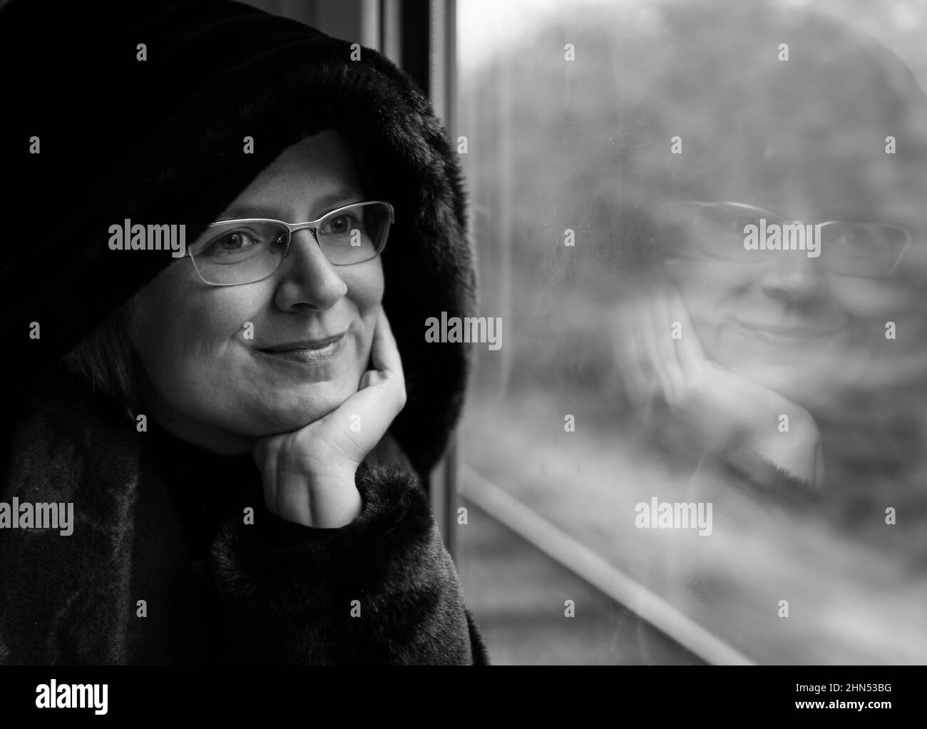 Zellik, Flemish region / Belgium - 04 20 2019: Attractive thirty year old woman looking out of the window of a local train with a furry coat Stock Photo